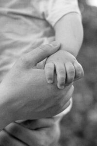 baby-haende.shooting-fuerth Detailaufnahme: Frau hält Babyhand auf Wiese.