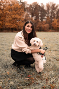 familie-outdoor-fuerth Frau sitzt auf Wiese, streichelt Hund und sieht in die Kamera.