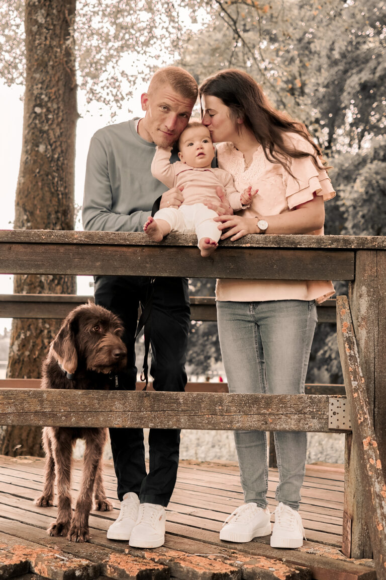 Familie steht auf Brücke im Stadtpark Fürth, hält Baby im Arm, Hund steht daneben.