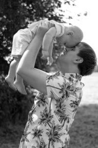 familienfotos-fuerth-wiese Papa hebt seinen Sohn in die Luft und berührt Stirn an Stirn auf Wiese in Fürth.