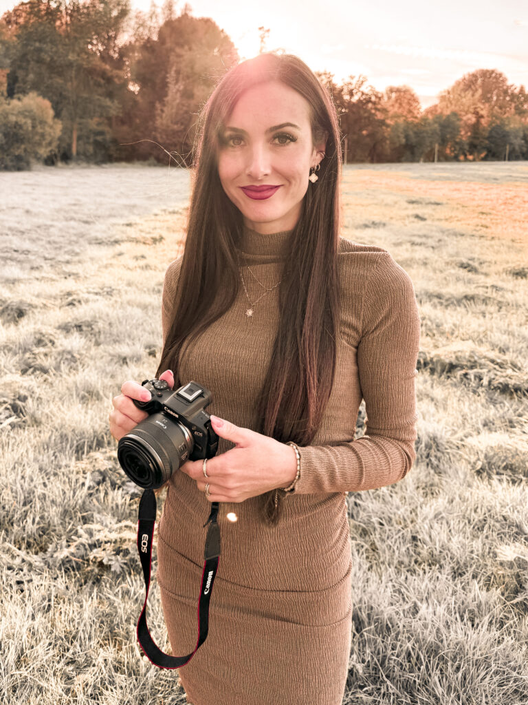 Frau mit Kamera steht im Sonnenuntergang auf einer Wiese in Fürth.