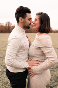 liebevolles-babybauchshooting-nuernberg Schwangere Frau im Stadtpark Nürnberg blickt ihren Mann an, während er seine Hand auf ihren Babybauch legt.