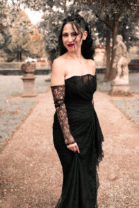 portrait-park-bilder-nuernberg Eine Frau im schwarzen Kleid steht im Park und lächelt.