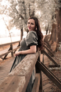 portrait-stadpark-abend-fuerth Eine Frau mit langen Haaren steht auf einer Brücke im Stadtpark Fürth und lehnt sich am Geländer an.