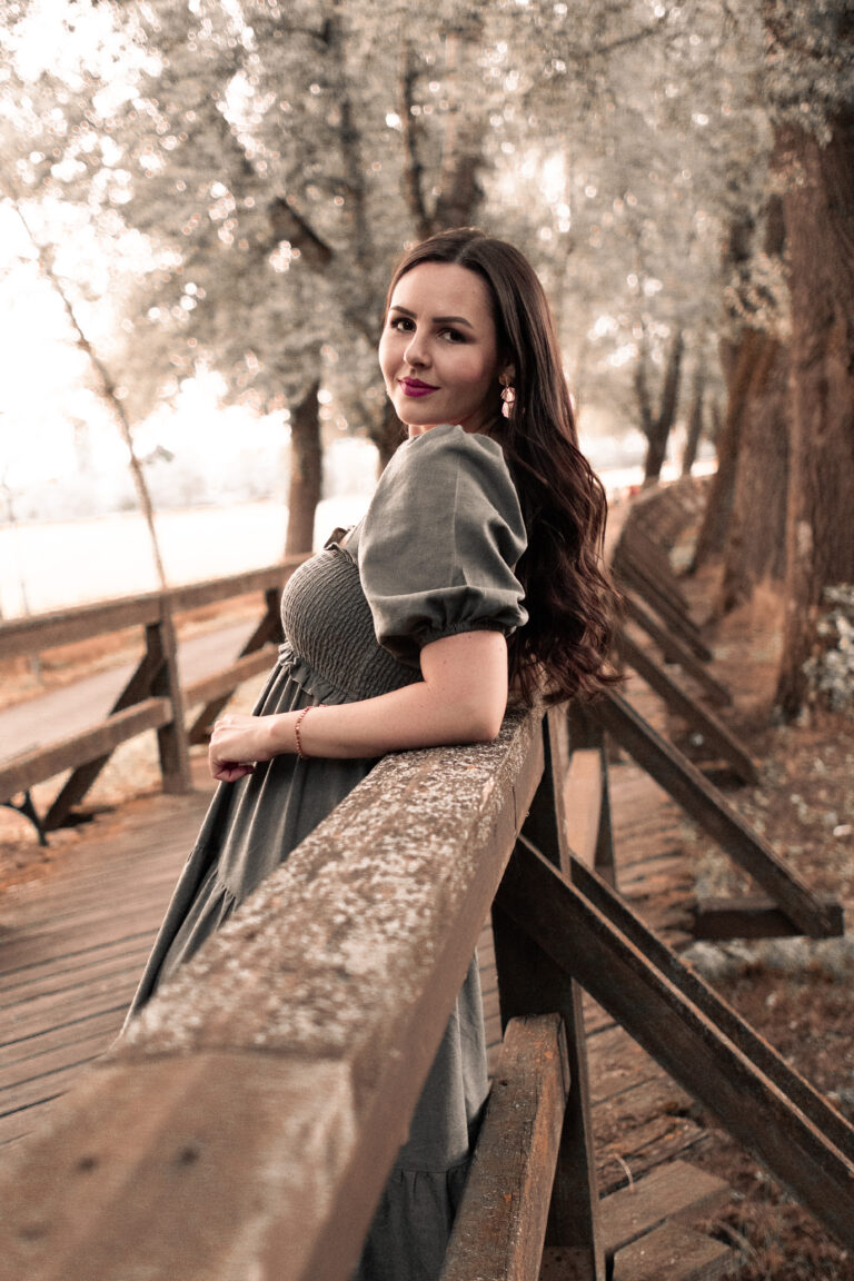 Eine Frau mit langen Haaren steht auf einer Brücke im Stadtpark Fürth und lehnt sich am Geländer an.