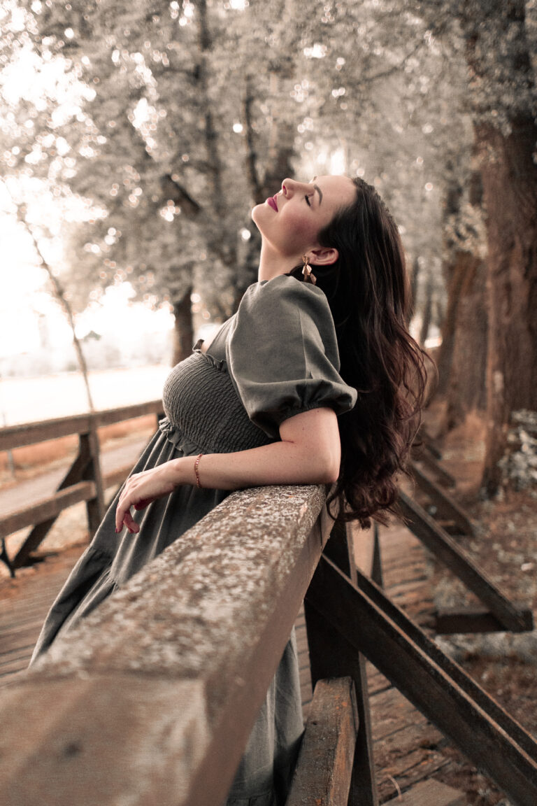 Frau lehnt auf Holzsteg an Geländer, stützt Ellbogen ab, lächelt mit geschlossenen Augen und blickt nach oben in Fürth.