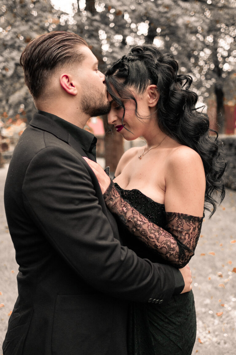 Ein Paar umarmt sich an ihrer Verlobungsfeier auf einer Wiese und küsst sich.